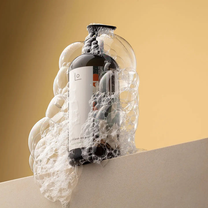 Hand Soap bottle with label partially submerged in water against a beige background