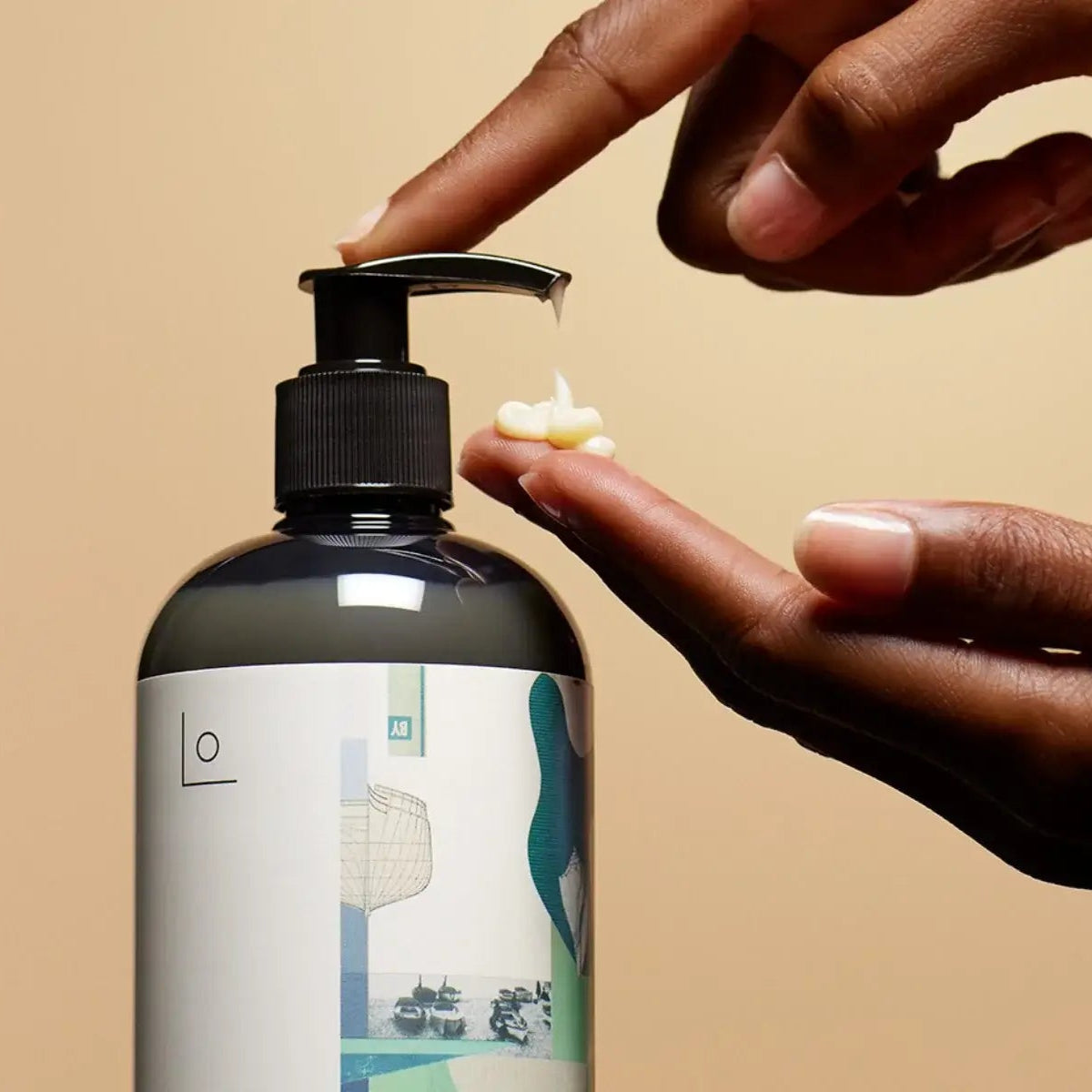 Hand applying lotion from a pump bottle against a beige background